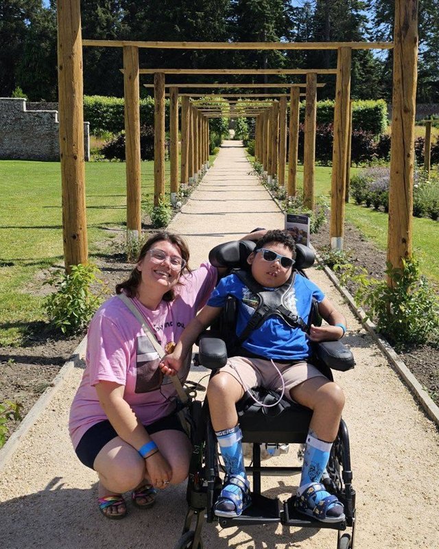 Hannah with her son on a sunny garden path under a wooden pergola