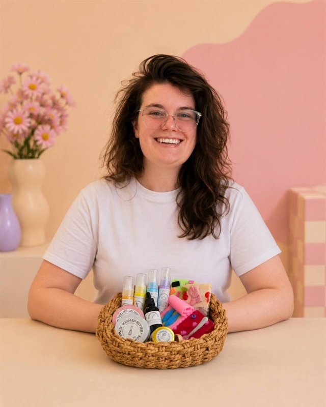 Hannah smiling at a table with a basket of Kitsch & Sink products